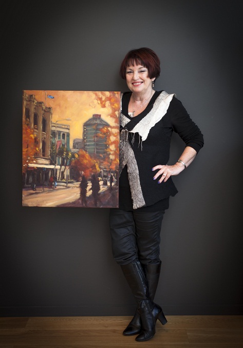 Denise Bryce with a McKenzie & Willis corner, High Street painting by Christchurch artist Philip Beadle.