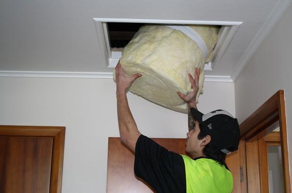 Adam Fletcher from Bay Insulation 2007 Ltd passes blanket insulation into the ceiling of a unit in the Tui Vale complex.