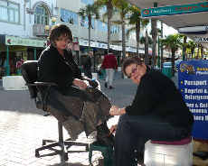 Left (being RAK'd - having shoes cleaned) Sally Muir and seated (gifting her time to clean shoes) Viv Blackmore from Napier Air New Zealand Holidays.