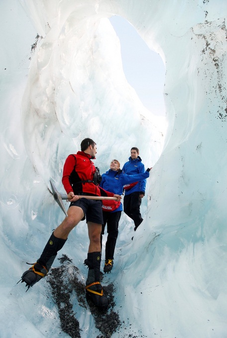 A guide from Franz Josef Glacier Guides takes visitors on an Ice Explorer heli hike through an ice tunnel.