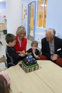 Executive Principal, Gillian Simpson, cuts the first anniversary cake with first pupils Annabel Close and Luka Mathews, while Tom Tothill, student at the original St Margaret's Pre-school in 1939, watches on.