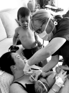 Two year old Rory watches as Franklin midwife, Megan Hurst, measures the head of his new sister Kora resting on mum, Ruth