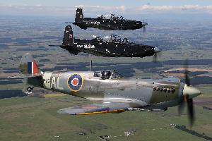 Supermarine Spitfire and two modern Beechcraft T-6C Texan II aircraft flying in formation