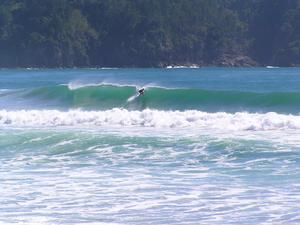 A surfer pulling into a left hand barrel in front of Hot Water Beach Rocks at the South end.