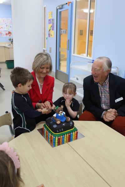 Executive Principal, Gillian Simpson, cuts the first anniversary cake with first pupils Annabel Close and Luka Mathews, while Tom Tothill, student at the original St Margaret's Pre-school in 1939, watches on.