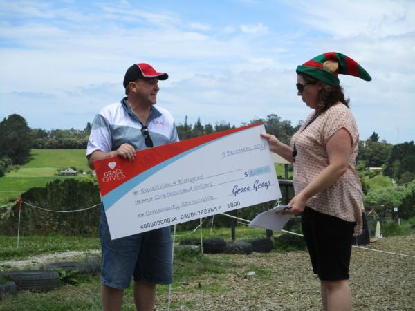 Equestrian 4 Everyone Chairperson, Sarah Sharp, receiving a $1000 "Grace Gives" grant from Grace Removals New Zealand, Auckland Branch Manager, John Scott.