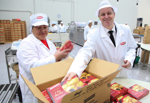 Prime Minister John Key helps Hansells Food Group employee No'o Pole to pack product.