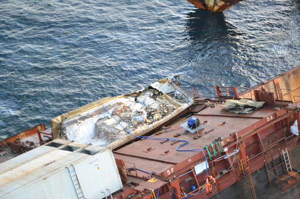 Salvors have cut off the top of a crushed container to access the contents and remove it from the wreck.