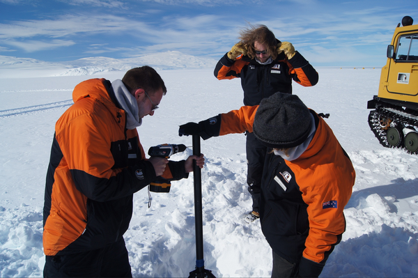 Adrian McDonald on left with a drill on the ice in Antarctica.