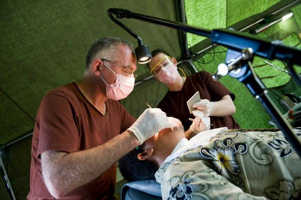 Major Martin James, oral surgeon, performs a dental procedure. Private Sarah Hughes assists.