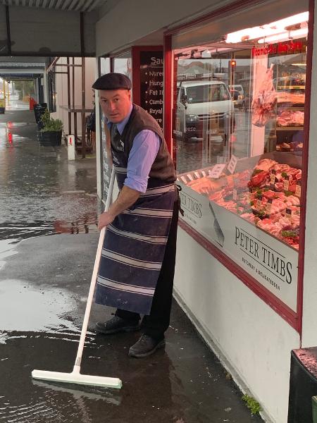 David Timbs cleaning up after floodwater breached his shop in July for the third time that month.