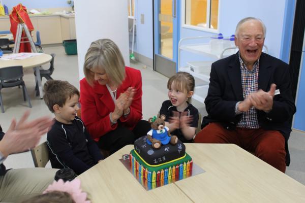 Executive Principal, Gillian Simpson, cuts the first anniversary cake with first pupils Annabel Close and Luka Mathews, while Tom Tothill, student at the original St Margaret's Pre-school in 1939, watches on.