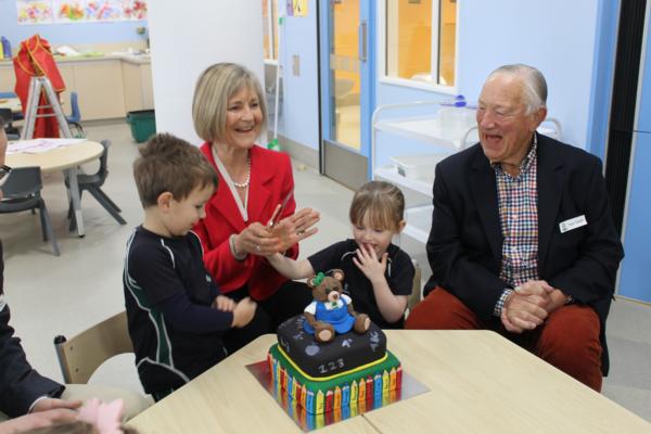 Executive Principal, Gillian Simpson, cuts the first anniversary cake with first pupils Annabel Close and Luka Mathews, while Tom Tothill, student at the original St Margaret's Pre-school in 1939, watches on.
