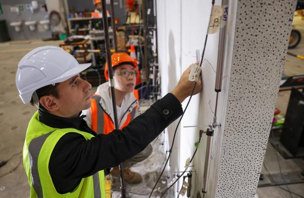 Dr Enrique del Rey Castillo and PhD student Victor Li measure the size of cracks in the concrete after the walls have been subjected to earthquake testing at the University of Auckland engineering laboratory.