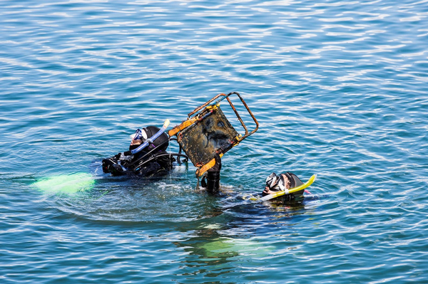 Divers haul a fisherman's chair out of the water. 