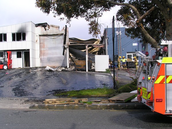 Fire fighters clean up after the Jones Odell Motor Bodies shop in Penrose was burned down