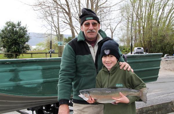 Proud father Dave Parr with son Charlie (beside boat) who caught this magnificent 2.4 kg rainbow at Lake Tarawera.