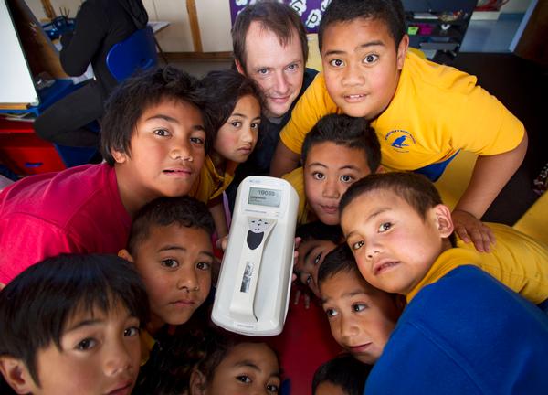 Dr Ian Longely and school children look at the air quality instrument