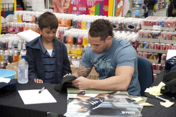 international rugby star Luke McAlister, With James Witten, 6, at The Warehouse, Albany where he met with fans to say hi and autograph Mitre caps and shoes.