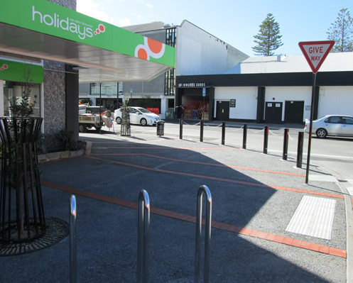 Corner of Hastings and Station streets &#8211; complete with exposed aggregate footpath with red clay paving bands, bike stands, trees, bollards and rubbish bin.