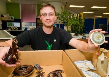 Mr Schrader at work with a collection of ceramics. He is holding part of a teapot in one hand, and the lid of a 19th century toothpaste jar in the other.