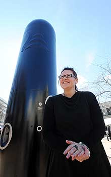 Maori visual artist Rachael Rakena stands next to  the black pou of Haka Peep Show in Dunedin. 