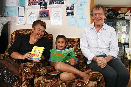 Flat Bush School pupil Meni Manase at home with his summer reading collection in last year's project; and Professor Tom Nicholson (right) visiting Meni with Flat Bush board of trustees chair Tofa Paniani.